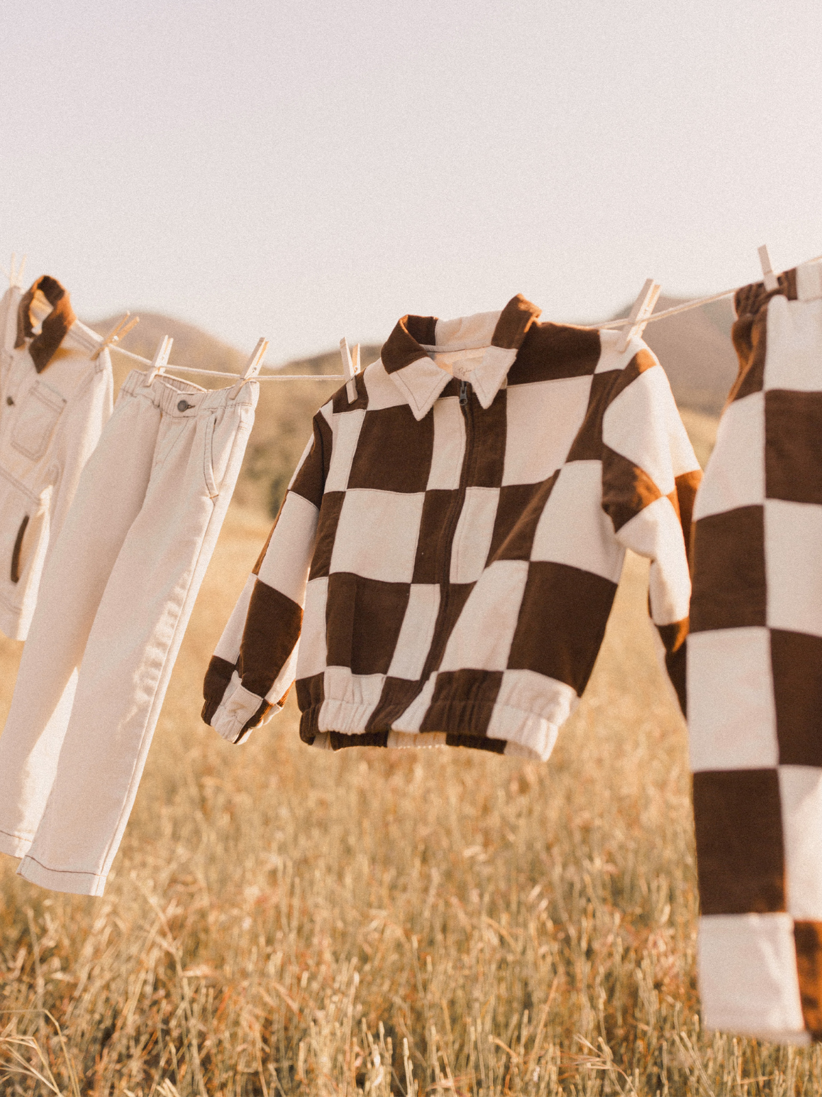 Brown and white checkered clothing hanging on a clothesline in a golden field.