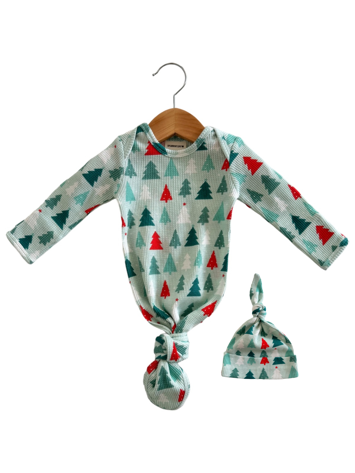 Green and red Christmas tree baby outfit with hat, hanging on a wooden hanger.