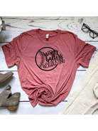 Pink t-shirt with the phrase "Raising Ballers is Exhausting," displayed on a wooden surface with shoes and glasses.