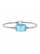 Silver bracelet featuring a large, faceted blue gemstone, elegantly designed on a white background.