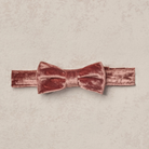 Pink velvet bow tie on a textured background, ideal for formal events and stylish attire.