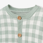 Green and white checkered sweater with a round neckline and wooden buttons.