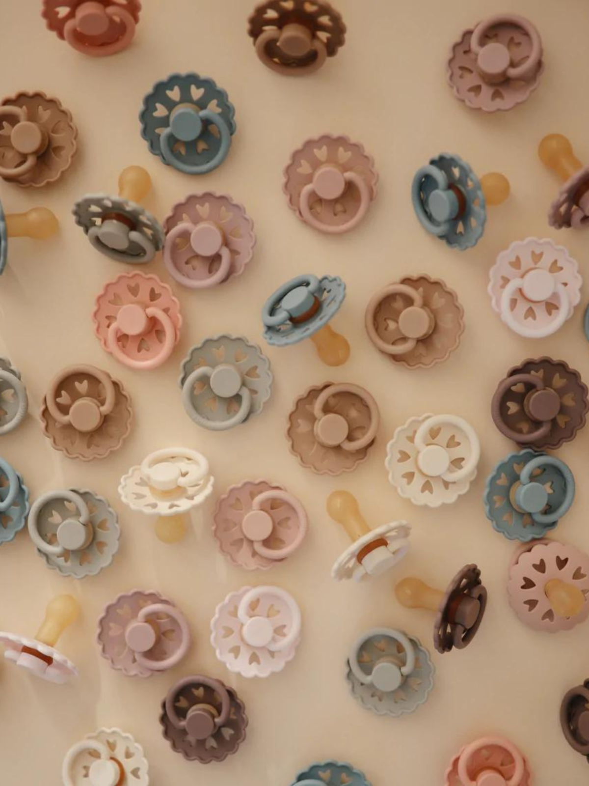 Colorful pacifiers in various shades scattered across a light background.