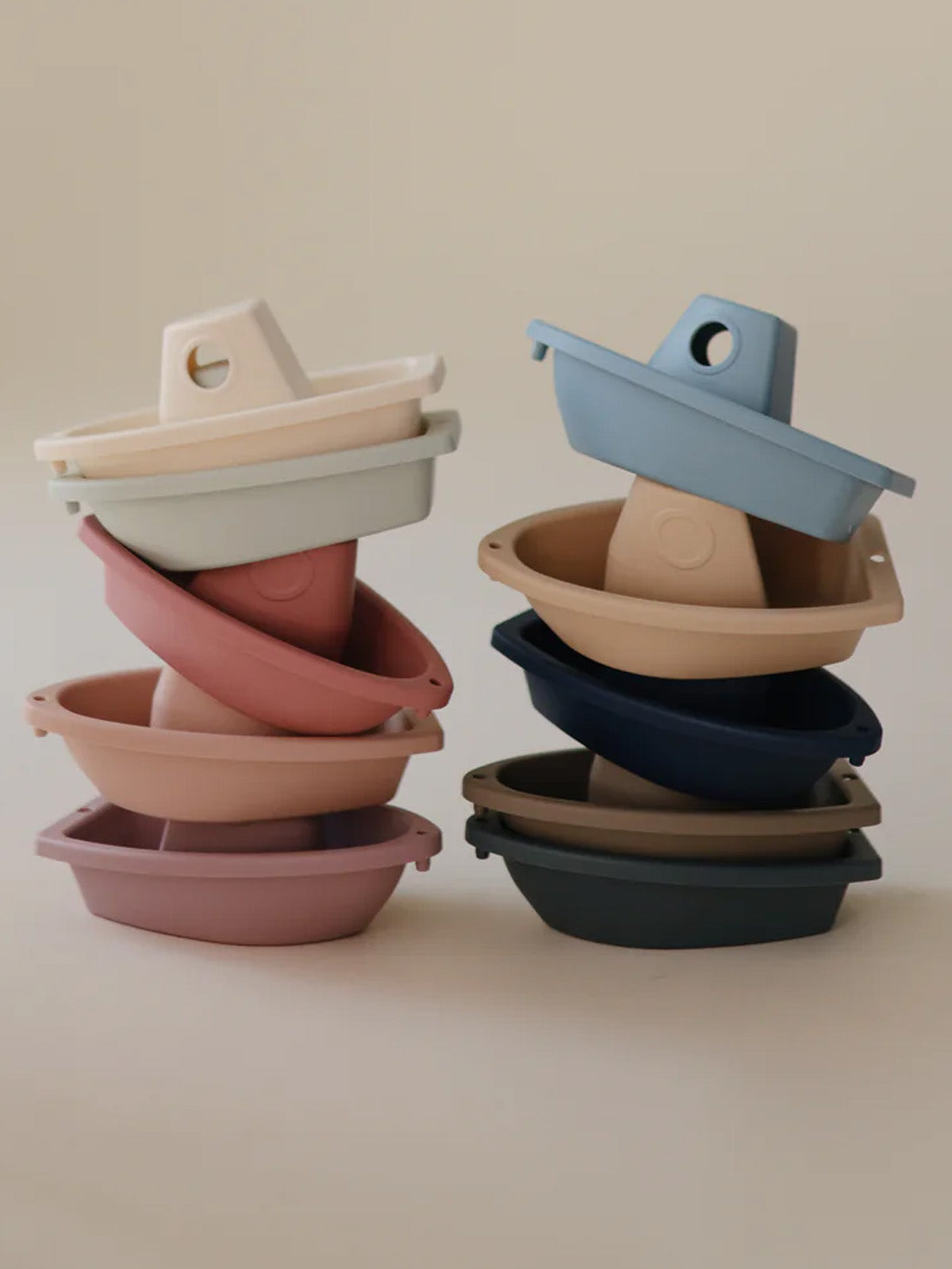 Stacked colorful silicone boat-shaped containers in various pastel shades against a neutral background.