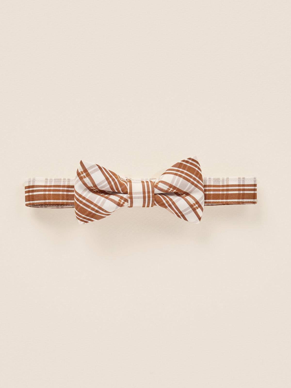 Brown and white striped bow tie on a light background. Perfect accessory for formal attire.