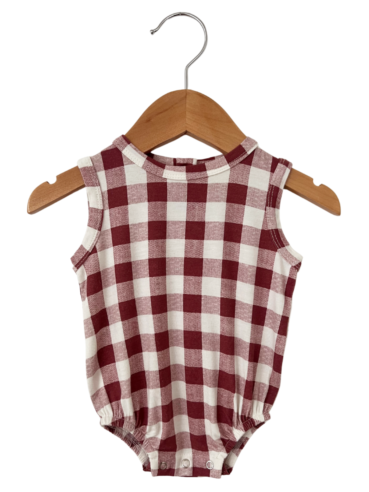 Red and white checkered baby onesie hanging on a wooden hanger.
