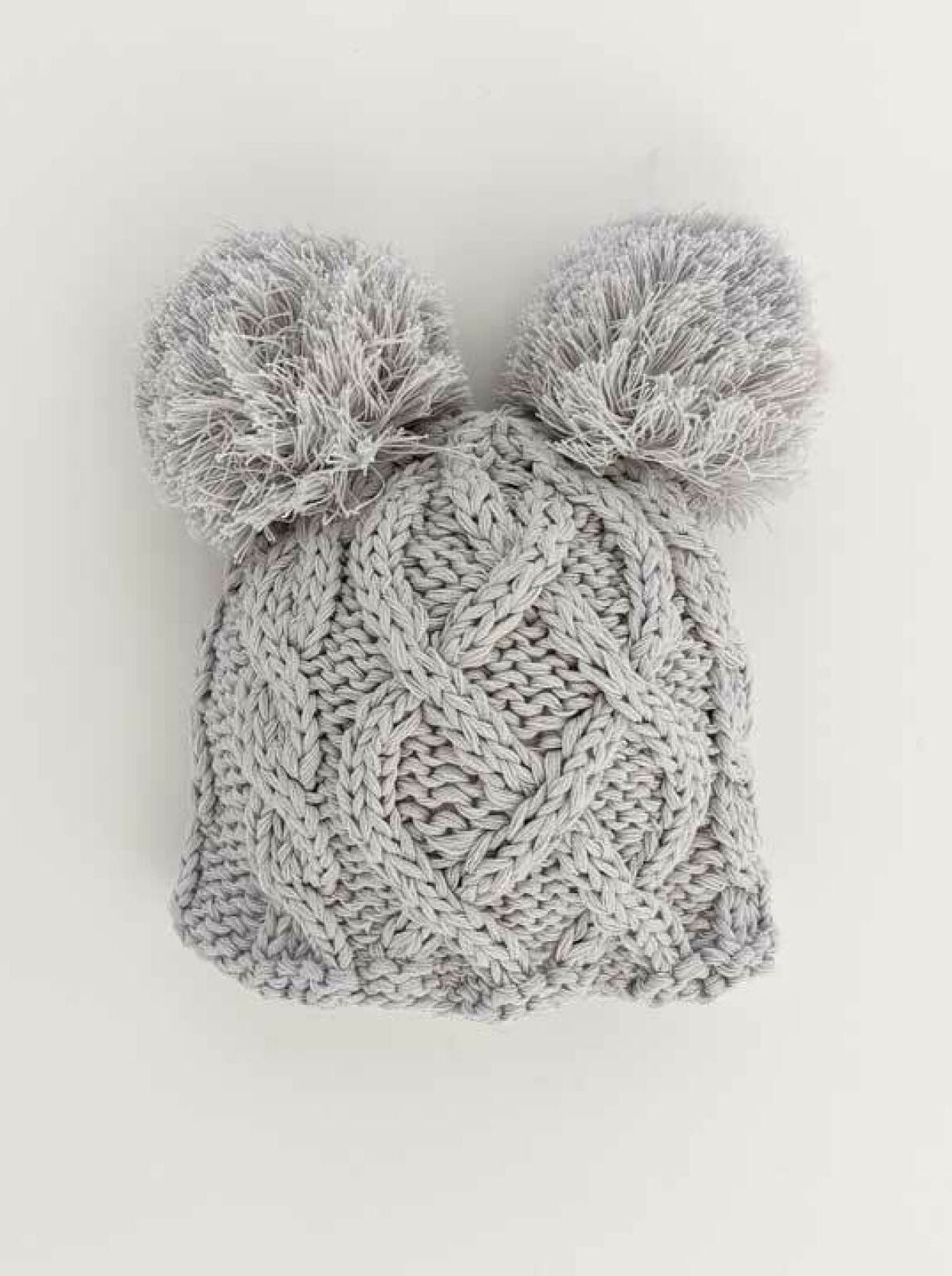 Gray knitted beanie with two fluffy pom-poms on top, showcasing a textured, woven pattern.