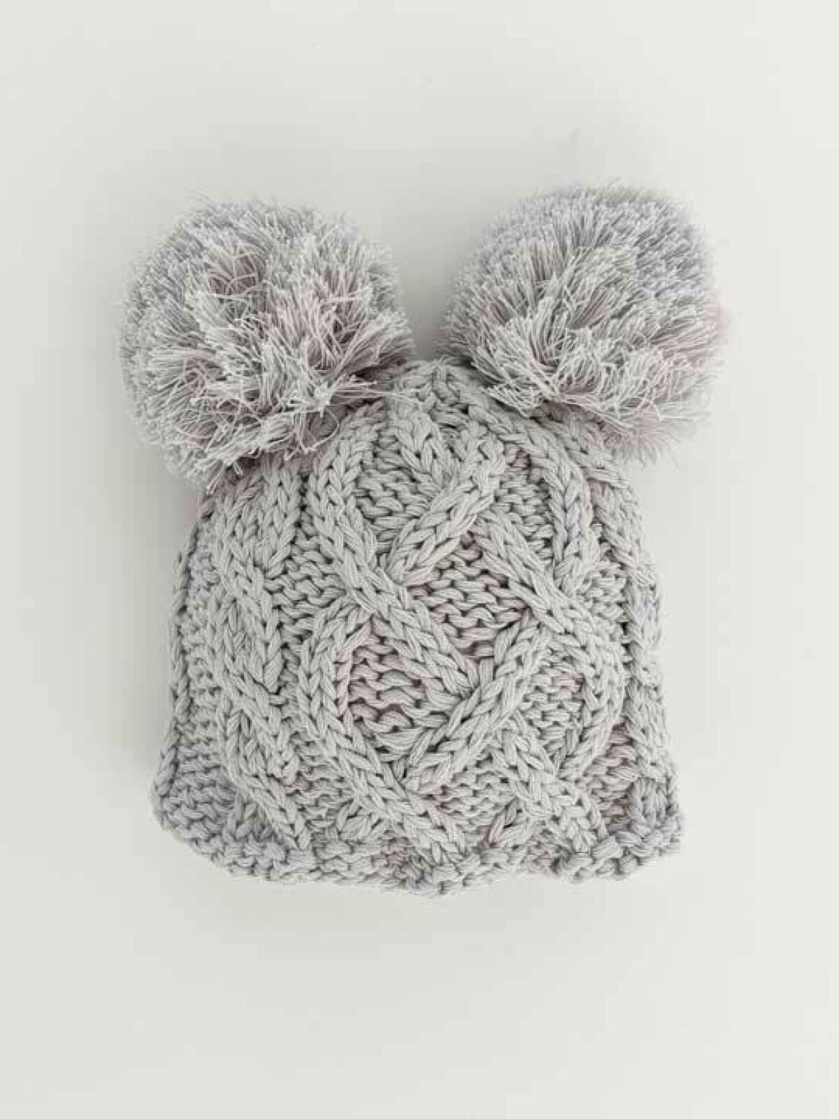 Gray knitted beanie with two fluffy pom-poms on top, showcasing a textured, woven pattern.