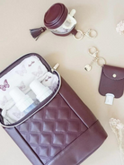 Brown quilted bag with baby bottles, a coin purse, and keychains on a beige background with flowers.