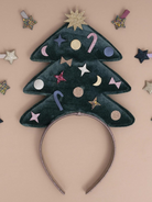 Festive green velvet headband shaped like a Christmas tree, adorned with colorful decorative elements.