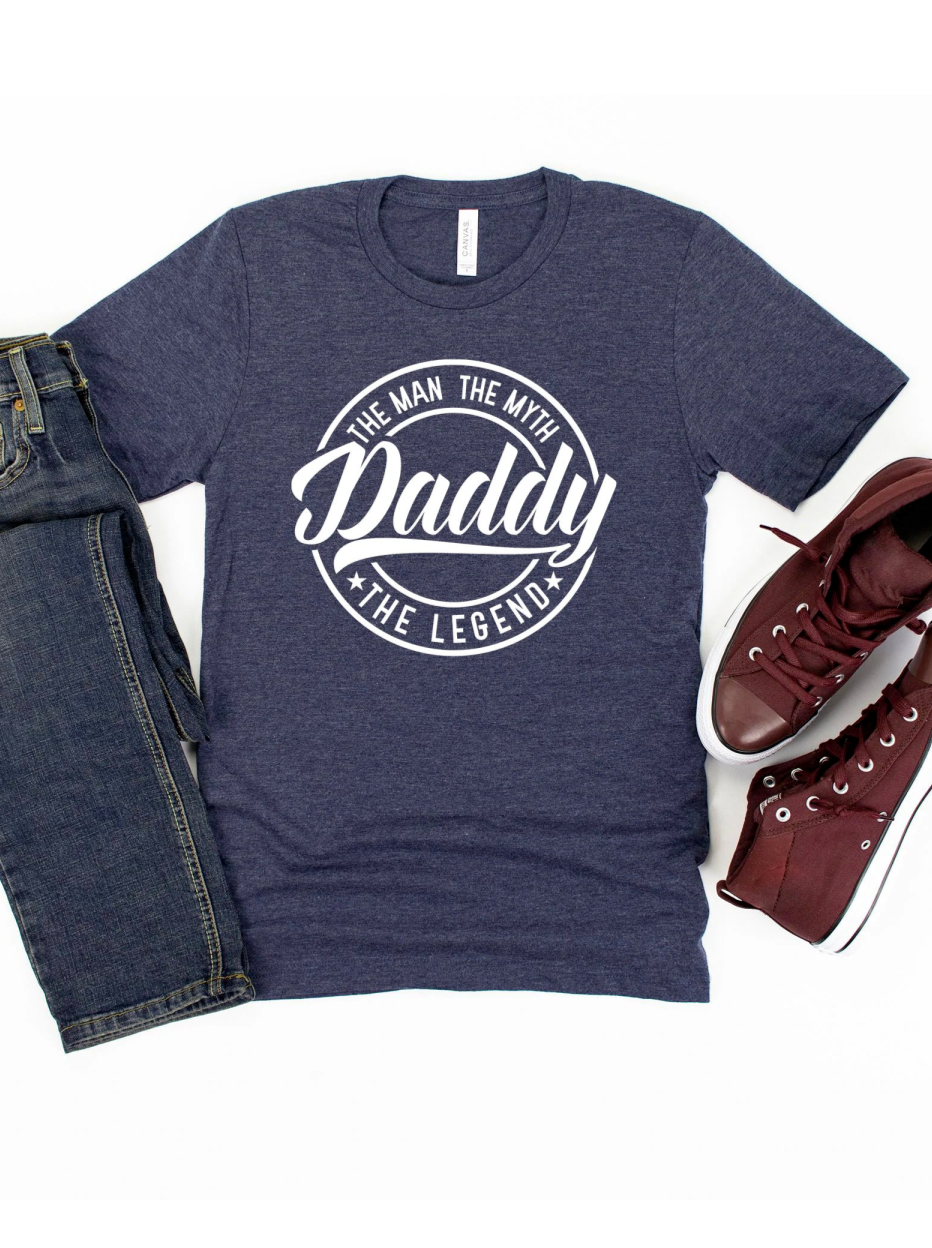 Navy t-shirt with "Daddy: The Man, The Myth, The Legend" text, paired with jeans and burgundy sneakers.