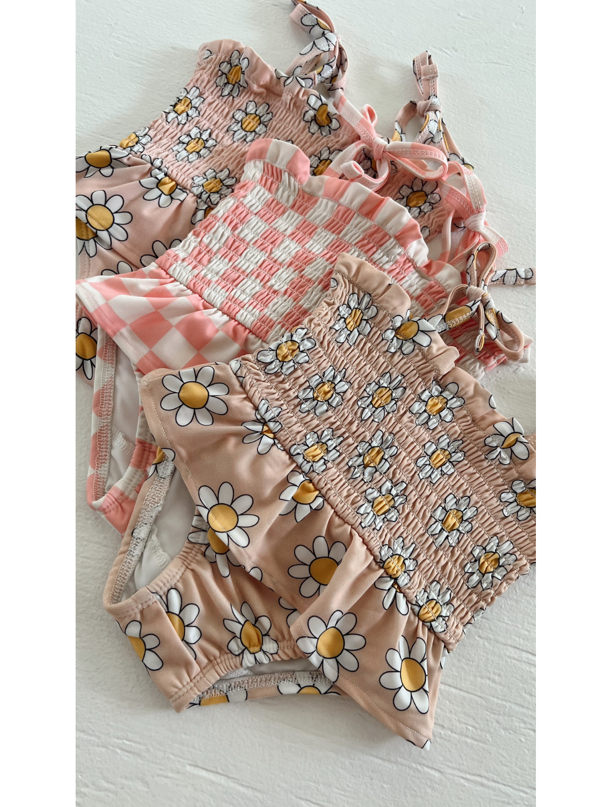 Four colorful swimsuits with floral and checkered patterns arranged neatly on a white surface.