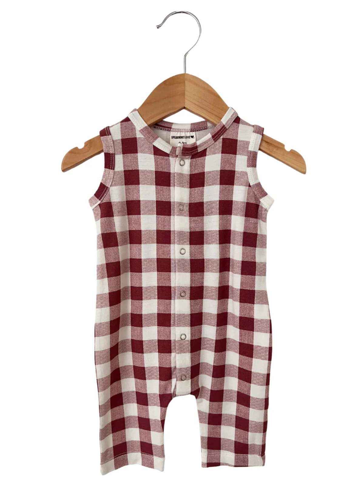 Red and white gingham check sleeveless romper hanging on a wooden hanger.