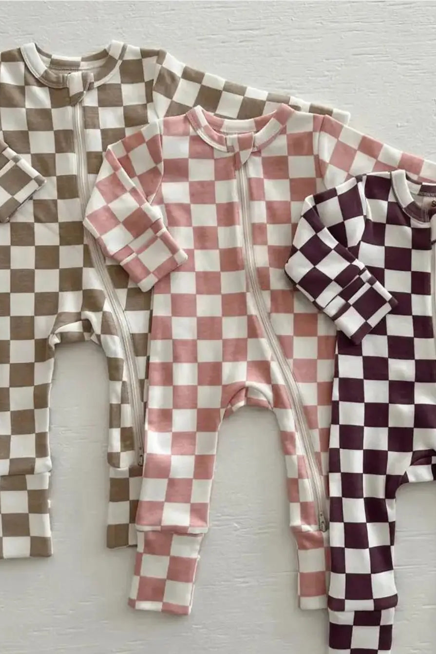 Three checkered baby rompers in brown, pink, and burgundy on a light wooden surface.