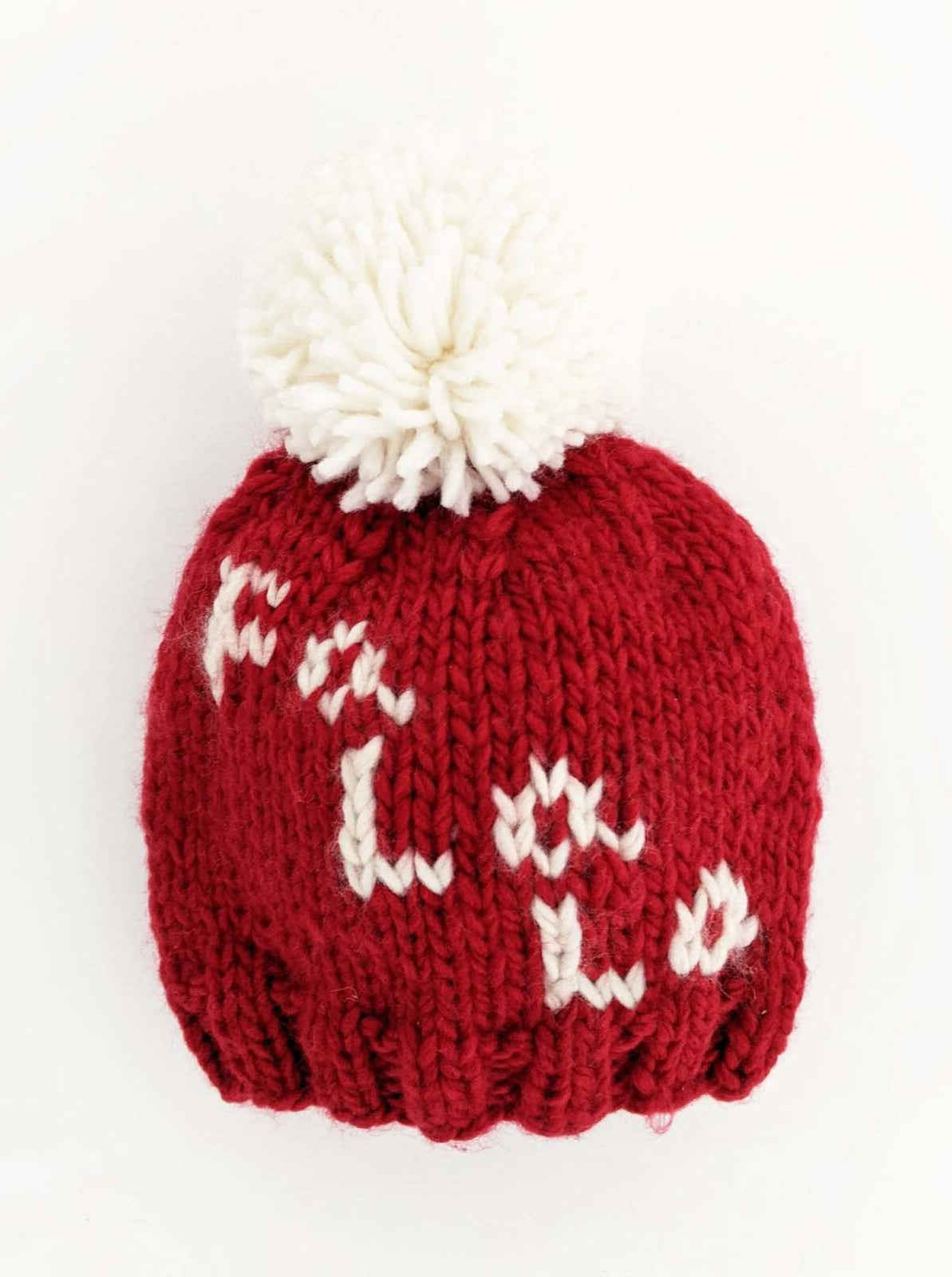 Red knitted beanie hat with a white pom-pom and the word "Hola" stitched in white.
