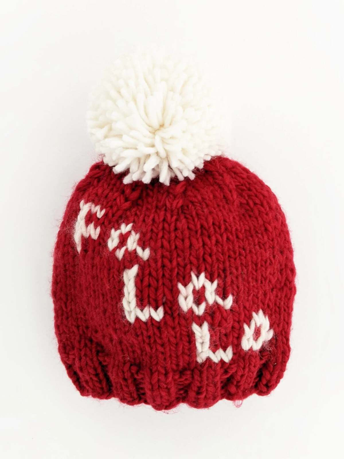 Red knitted beanie hat with a white pom-pom and the word "Hola" stitched in white.