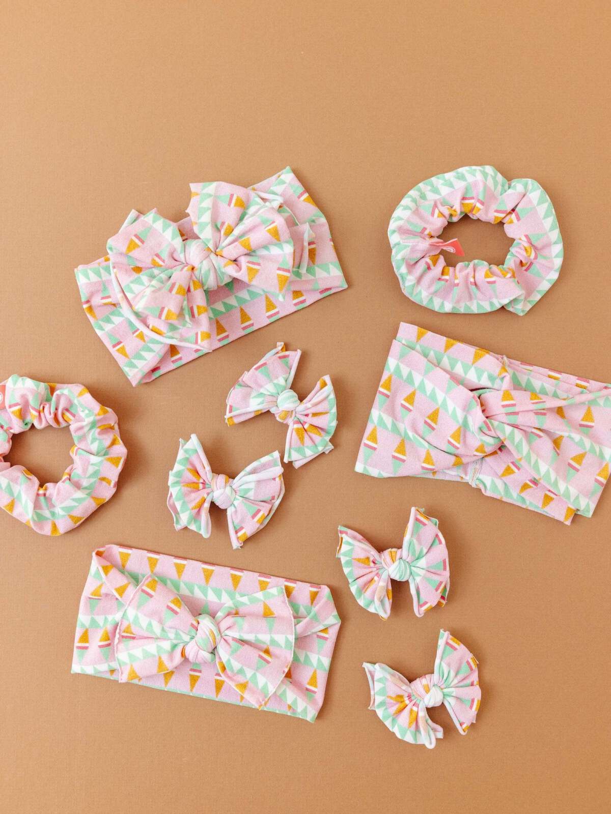 Colorful hair accessories including scrunchies and bows on a beige background.