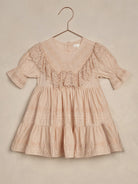 Light pink dress with lace detailing, hung on a copper hanger against a pale background.