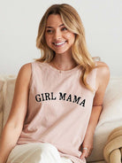 Smiling woman in a pink tank top that says "GIRL MAMA," seated on a cozy couch with soft fabrics.