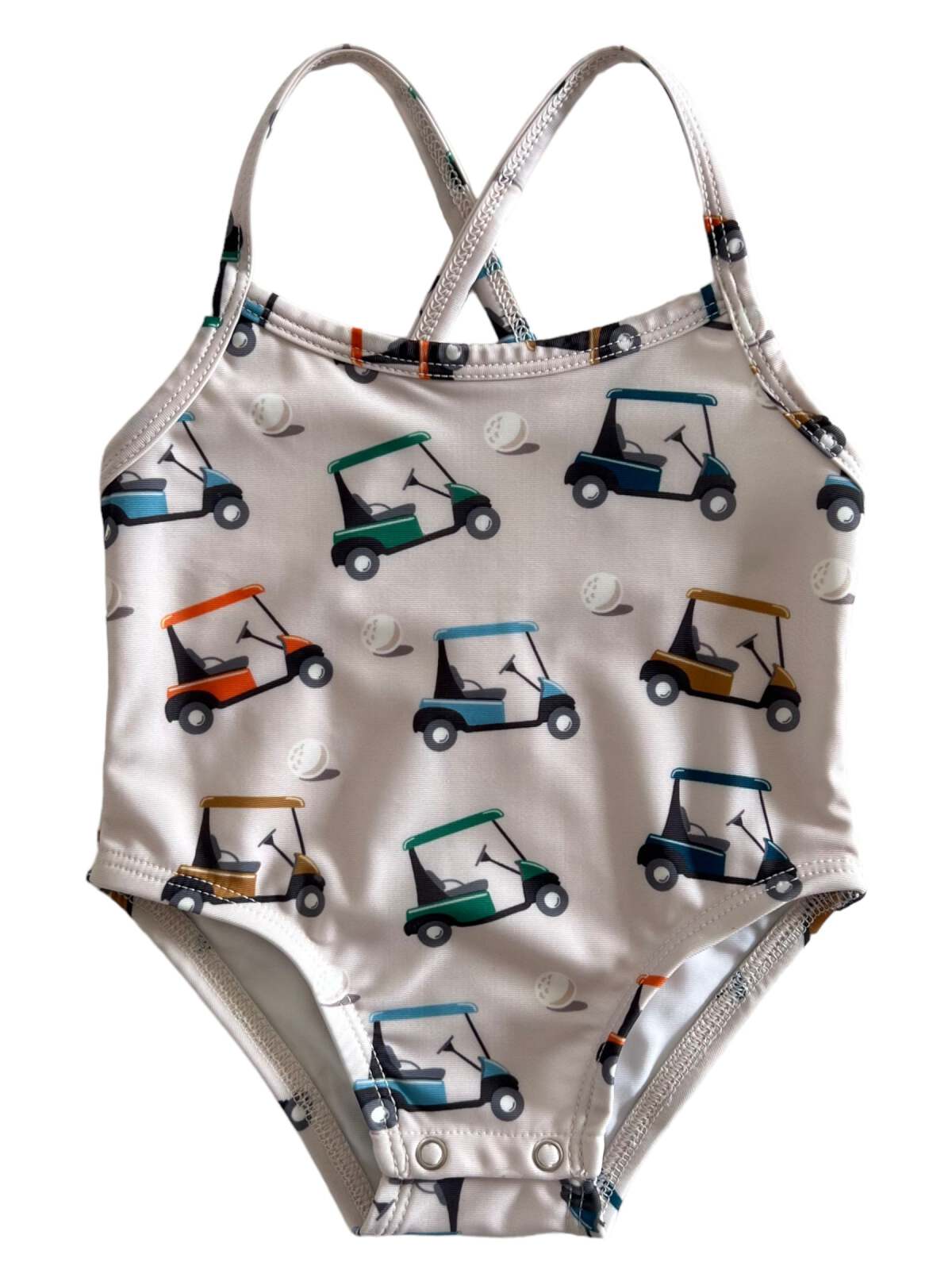 Kids' swimsuit featuring a fun print of colorful golf carts and baseballs on a light background.