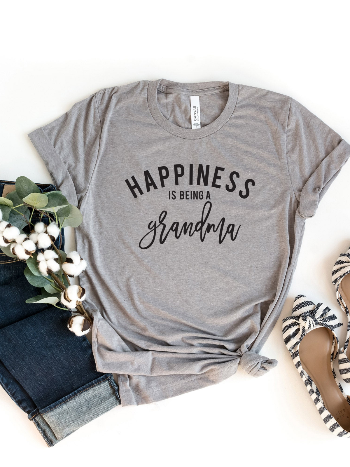 Gray t-shirt with "Happiness is being a grandma" text, paired with jeans and stylish shoes.