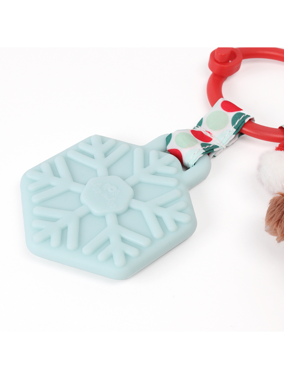 Light blue silicone toy shaped like a snowflake, attached to a red ring and a fluffy brown pom-pom.