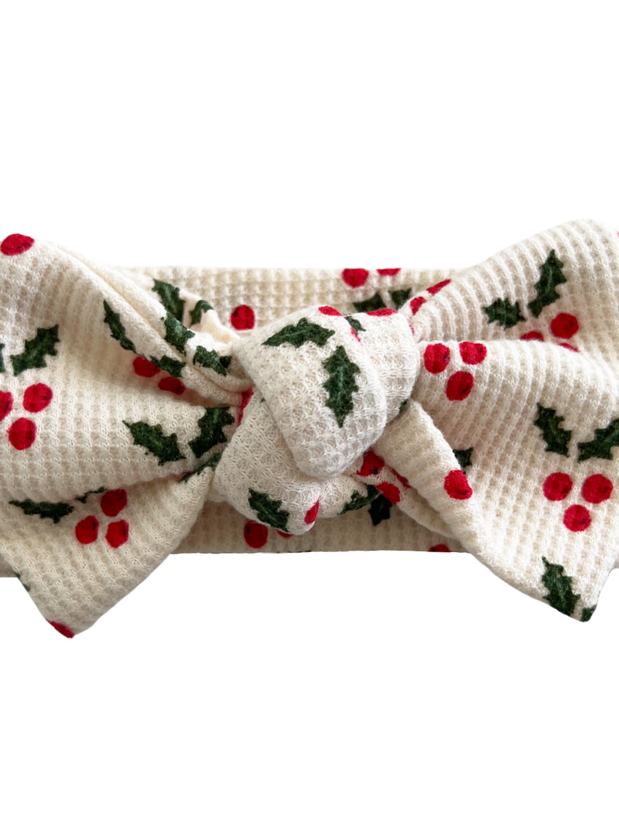 White headband with red berries and green leaves pattern, featuring a large bow in the center.