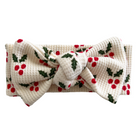 White headband with red berries and green leaves pattern, featuring a large bow in the center.