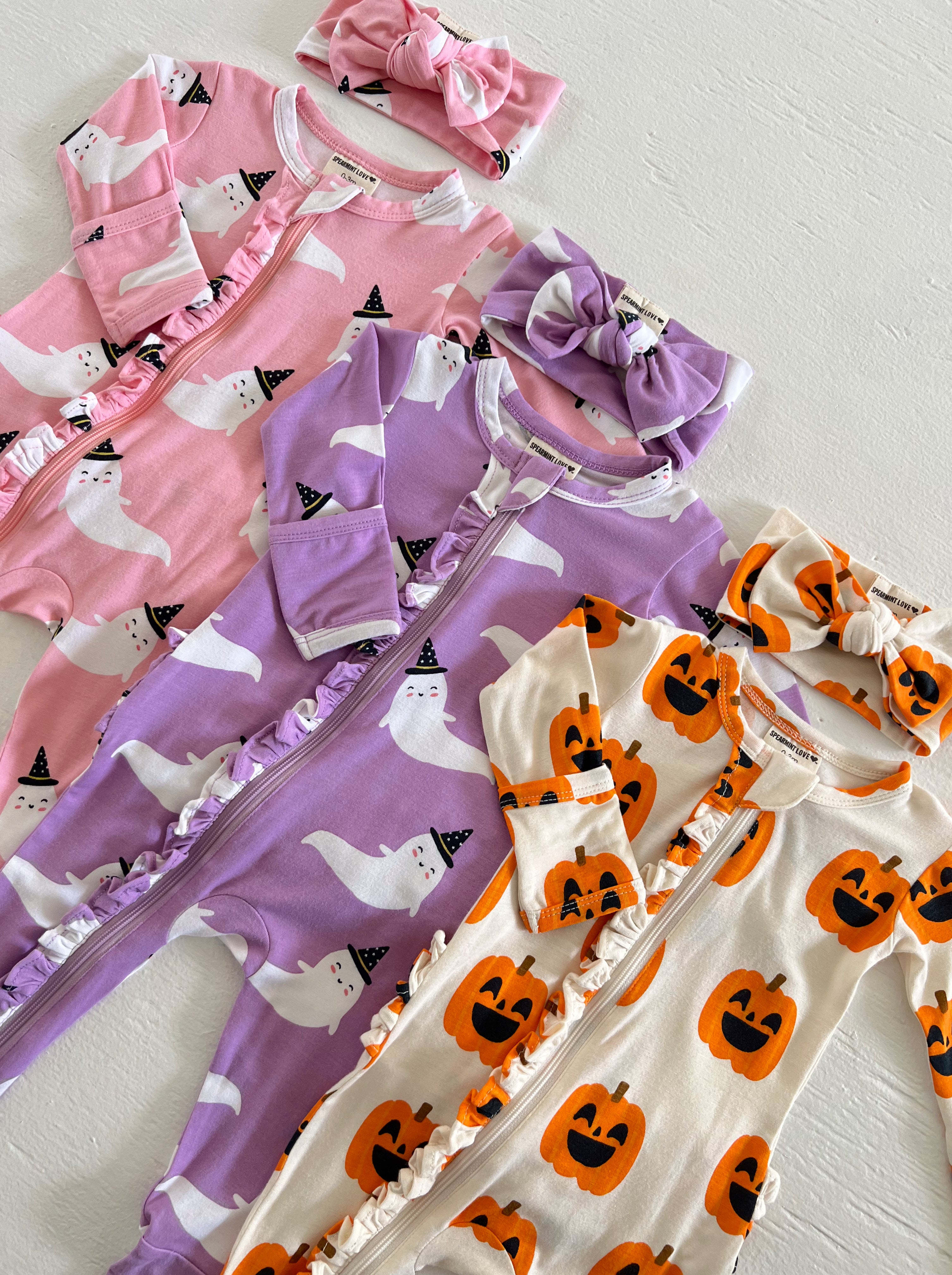 Assorted children's rompers and headbands with ghost and pumpkin designs, perfect for Halloween.