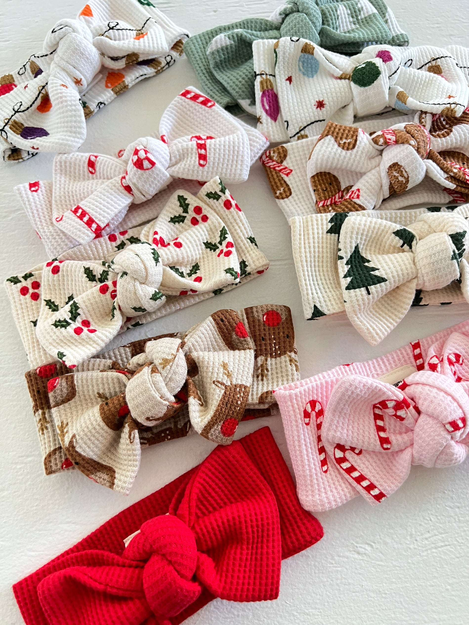 Colorful fabric bows with holiday themes, including candy canes, reindeer, and Christmas trees, arranged on a table.