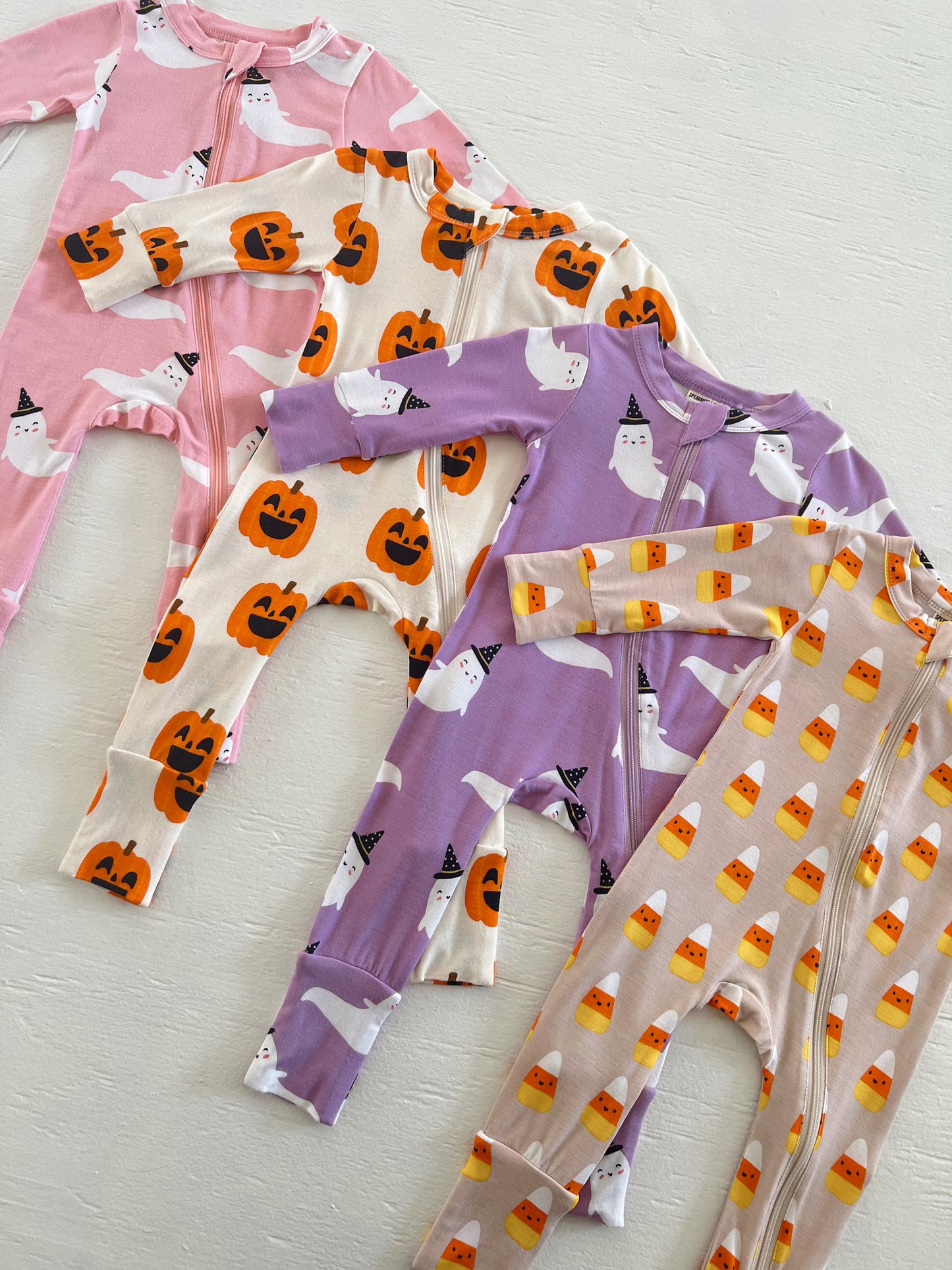 Colorful Halloween-themed children's pajamas featuring ghosts, pumpkins, and candy corn patterns.