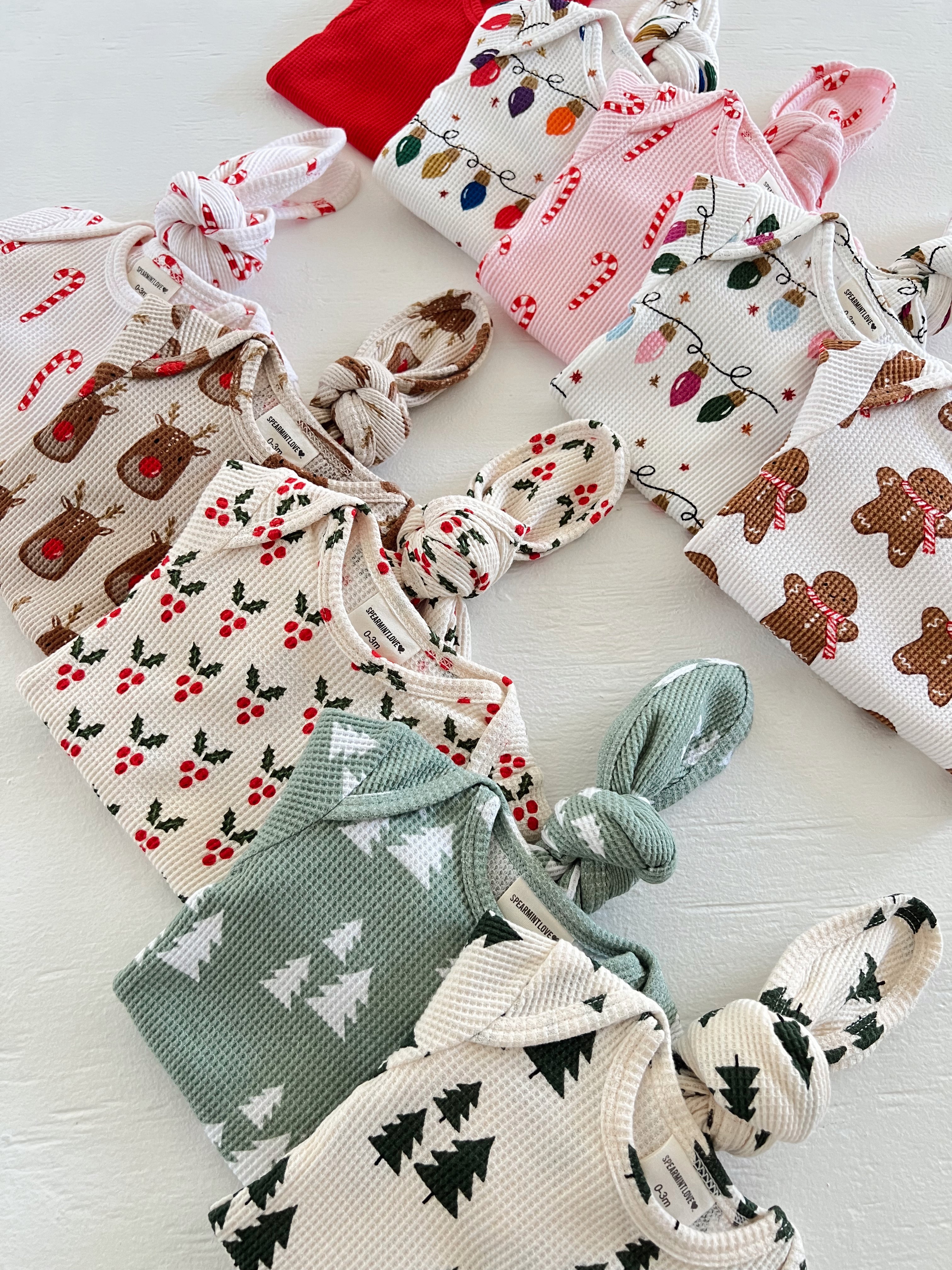 Assorted holiday-themed baby outfits with festive patterns, including candy canes and Christmas trees.