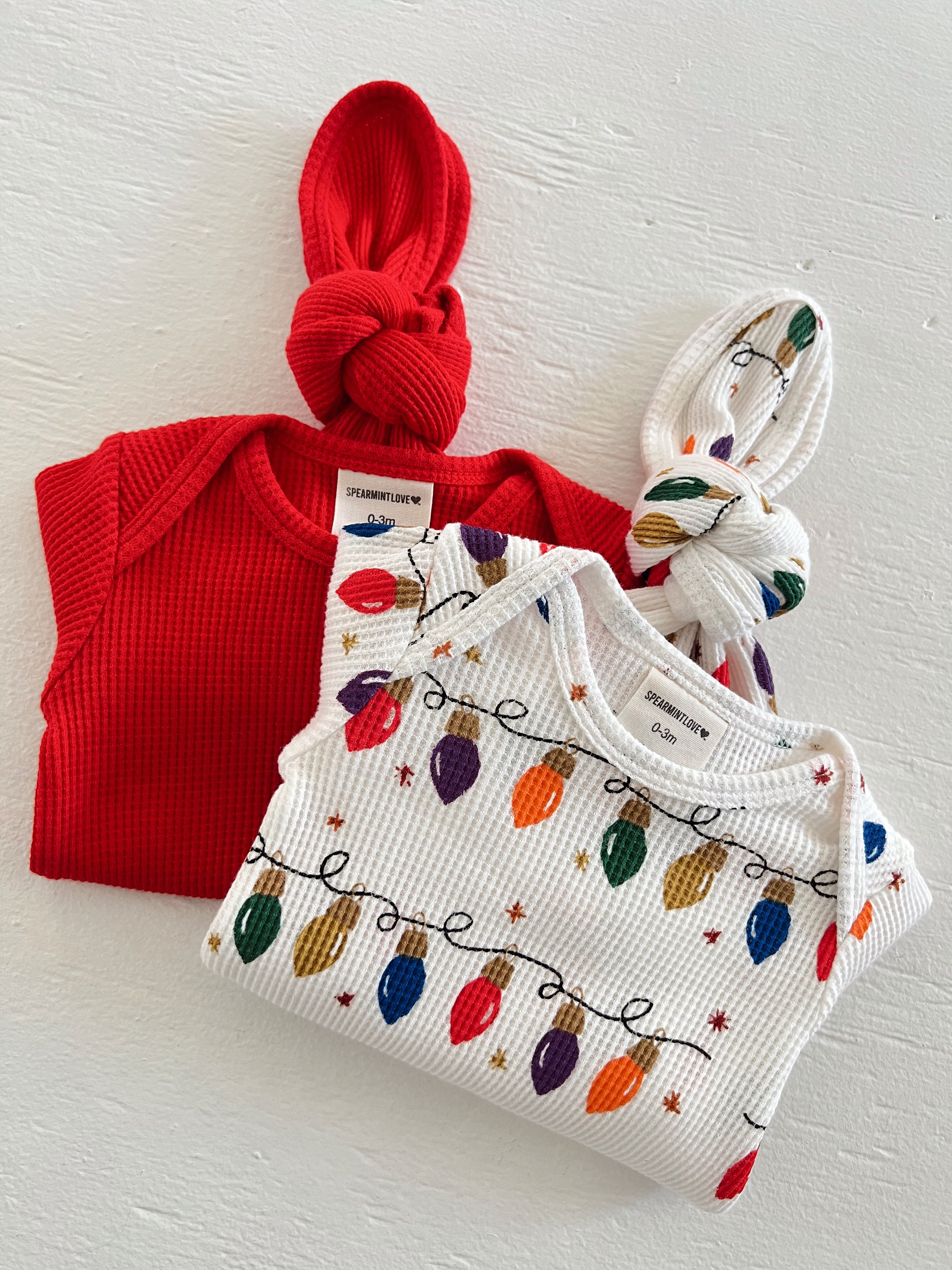 Red and white children's clothing with festive light patterns, neatly arranged on a white surface.