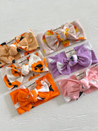 Assortment of colorful baby headbands with bows in various patterns and colors on a white background.