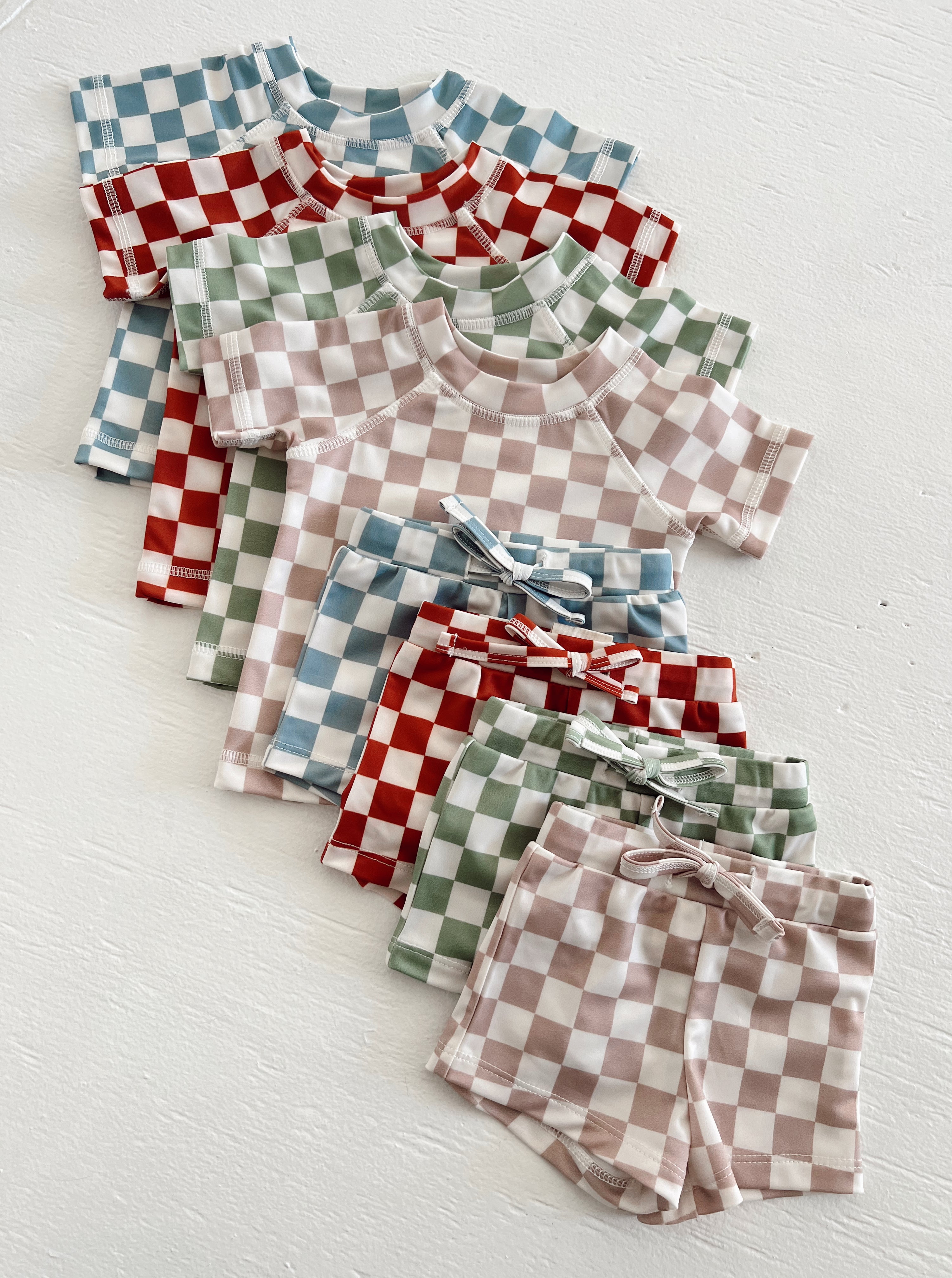 Colorful checked kids' clothing sets featuring short sleeves and matching shorts in various colors.