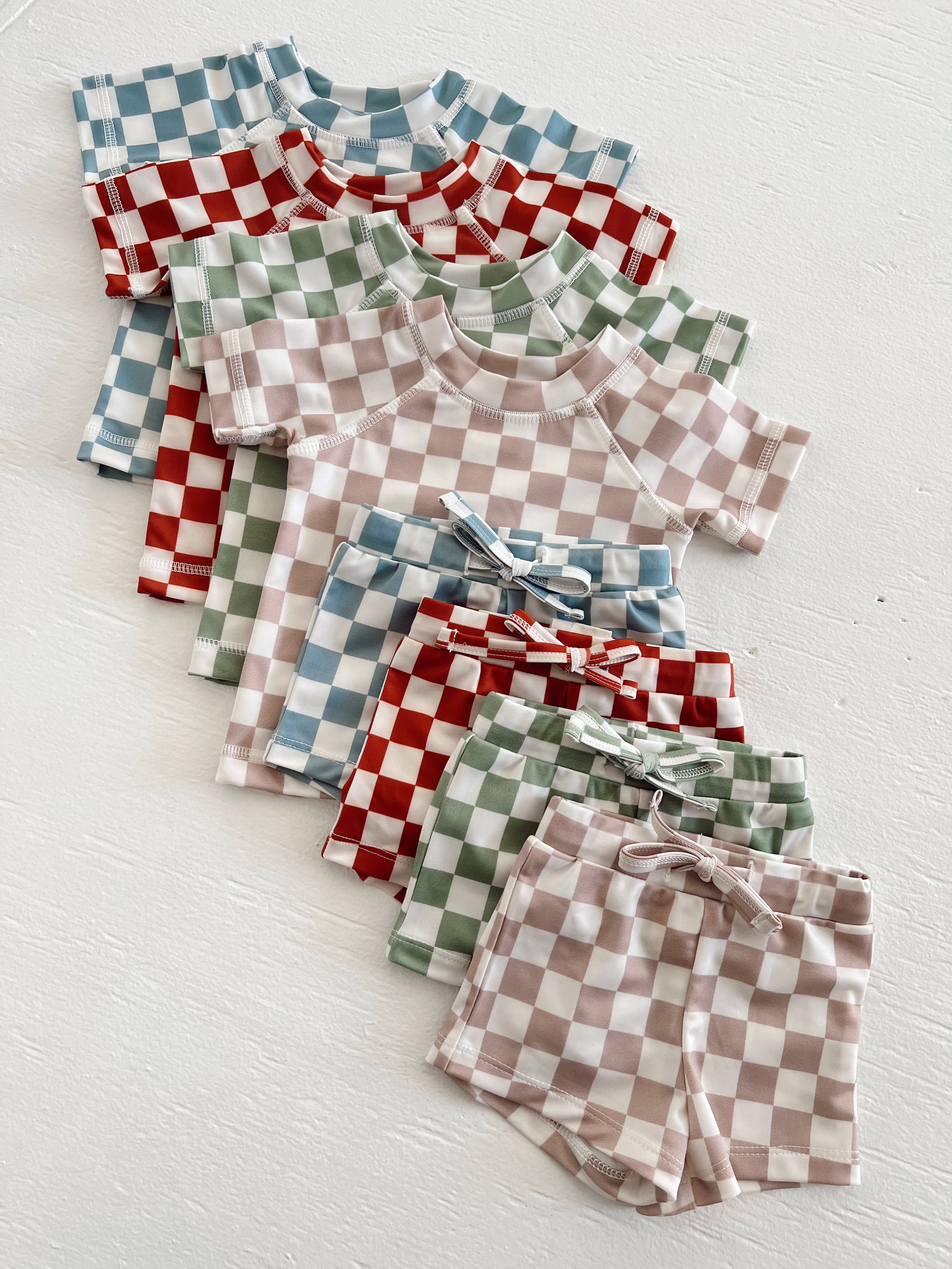 Colorful checked kids' clothing sets featuring short sleeves and matching shorts in various colors.