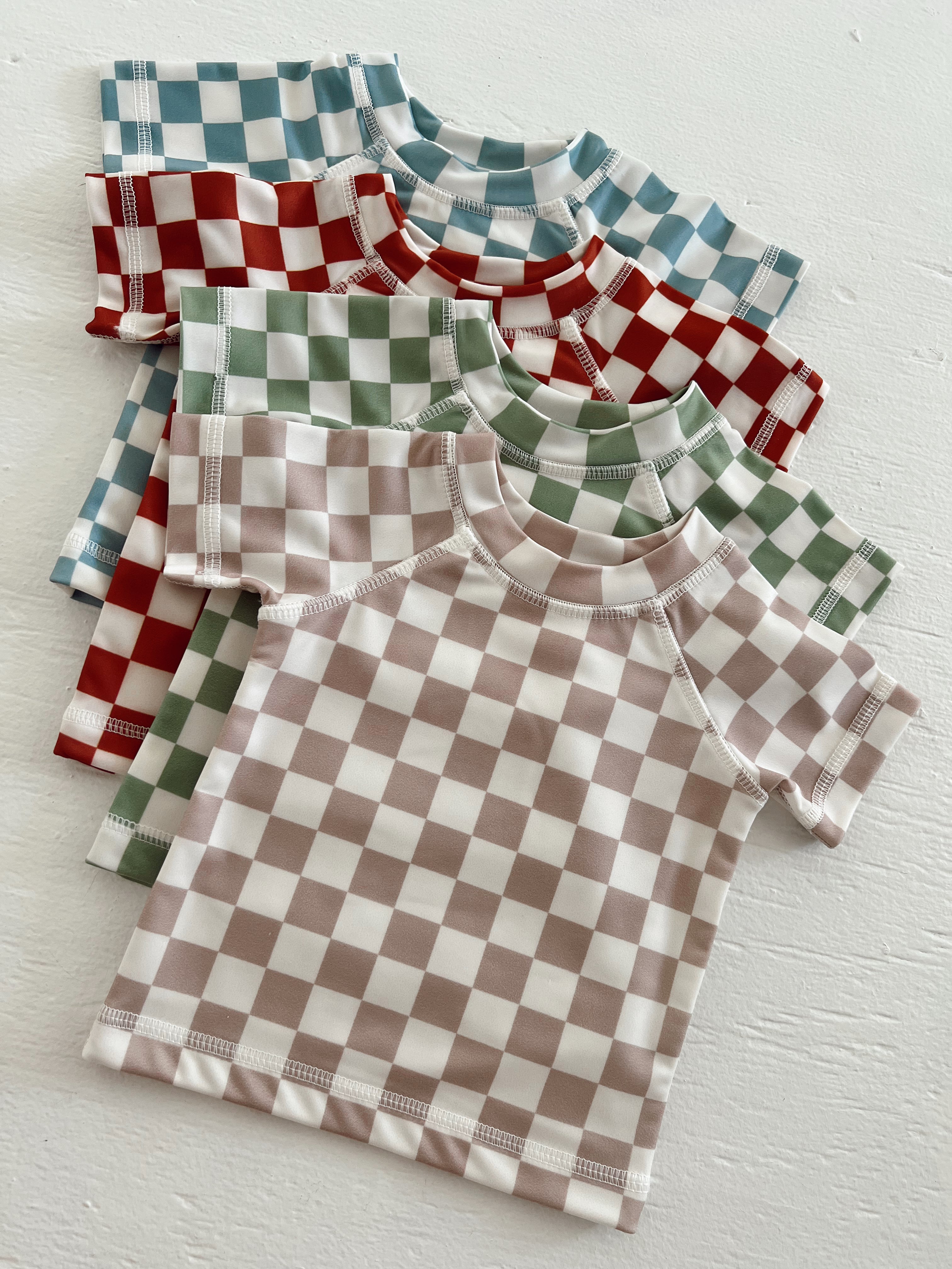 Colorful checkered shirts in red, green, blue, and brown arranged neatly on a light background.