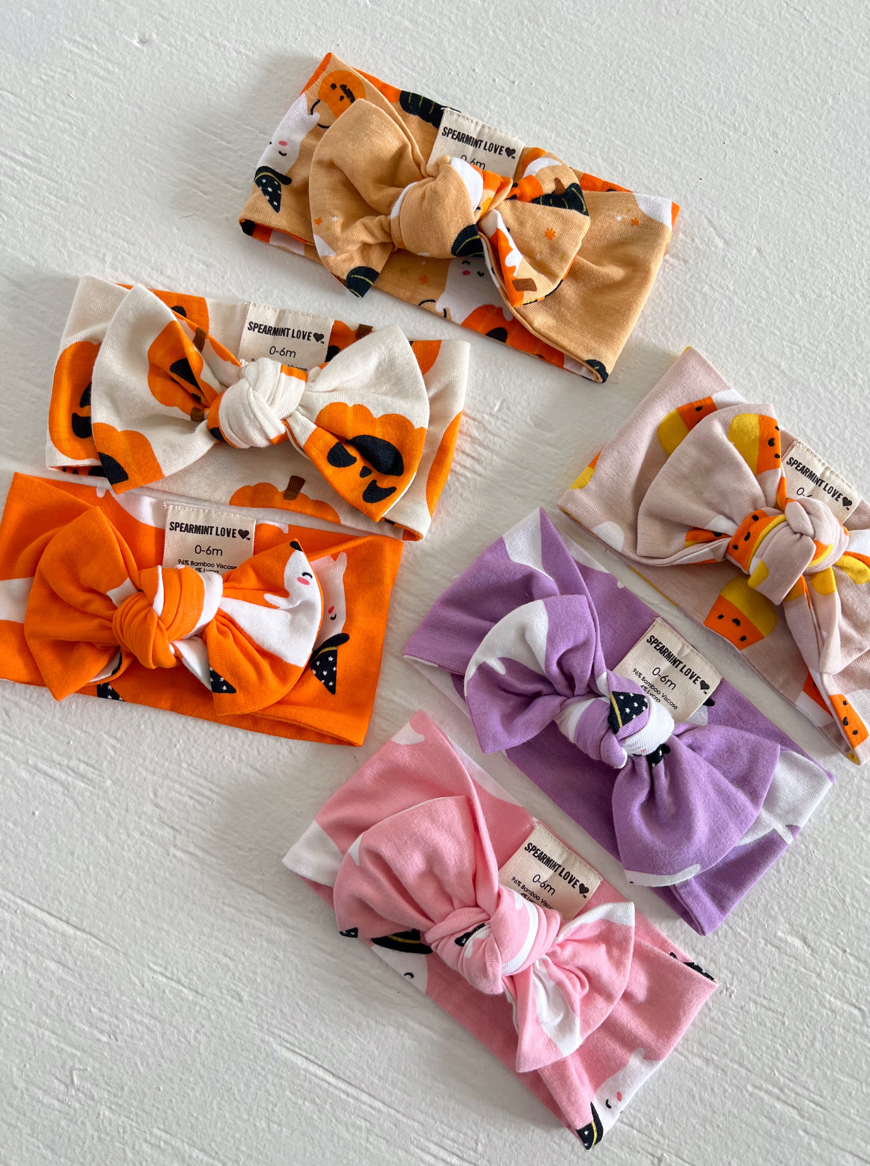 Six baby headbands featuring colorful patterns and bows, arranged on a light surface.