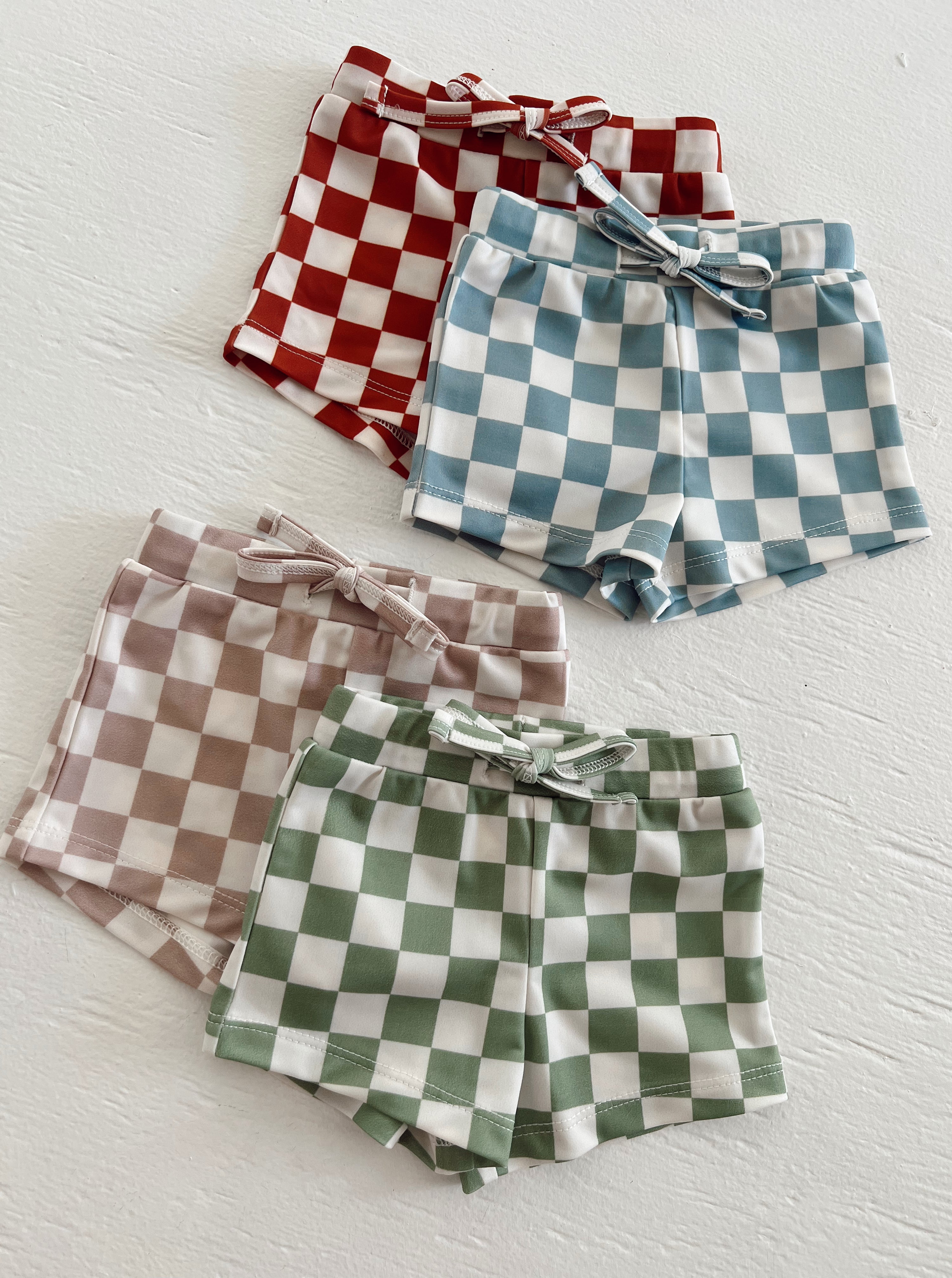 Colorful checkered shorts in red, blue, green, and brown arranged on a white surface.