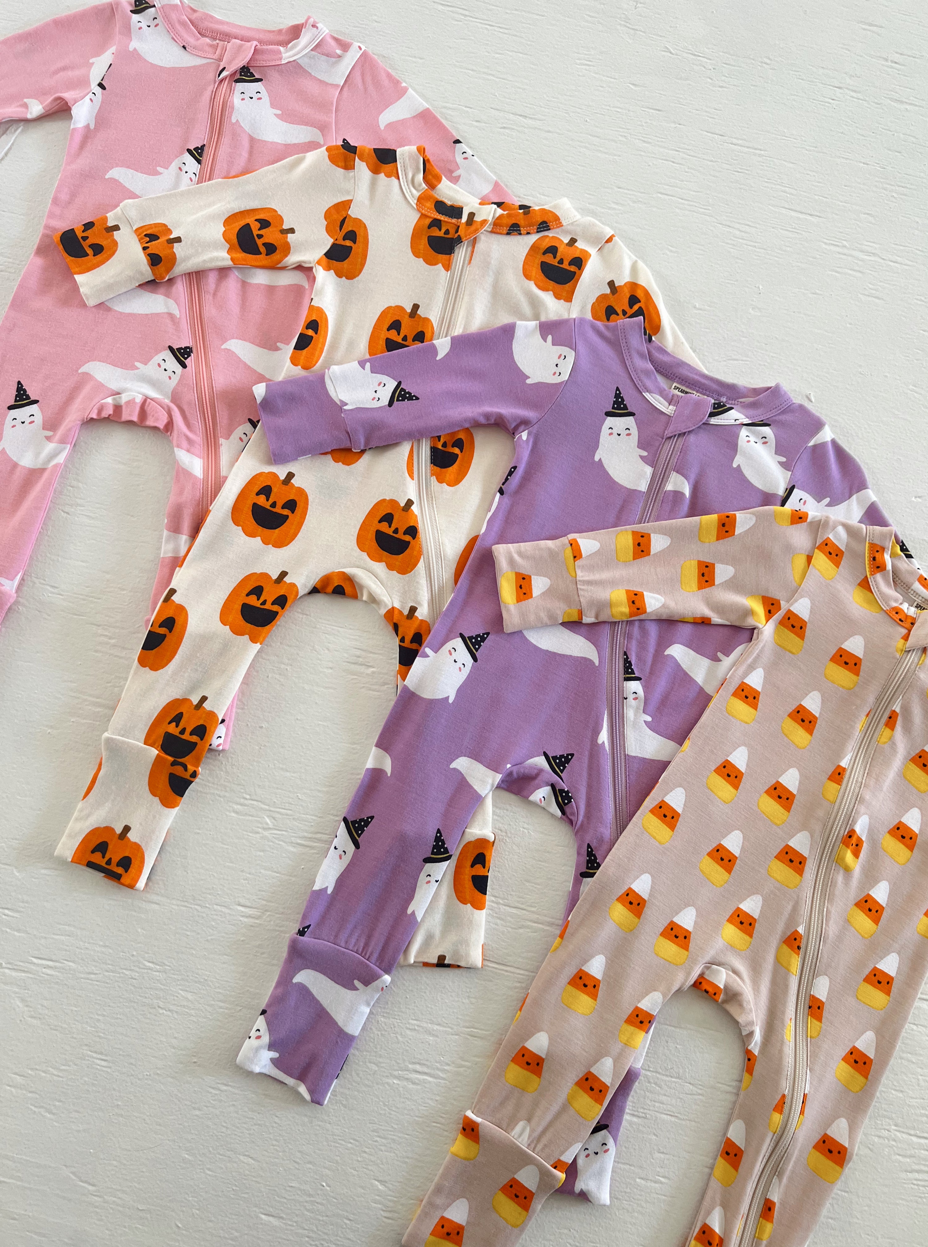 Colorful Halloween-themed baby pajamas featuring ghosts, pumpkins, and candy corn patterns.
