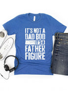 Blue T-shirt with text: “It’s not a dad bod, it’s a father figure,” paired with sneakers and jeans.