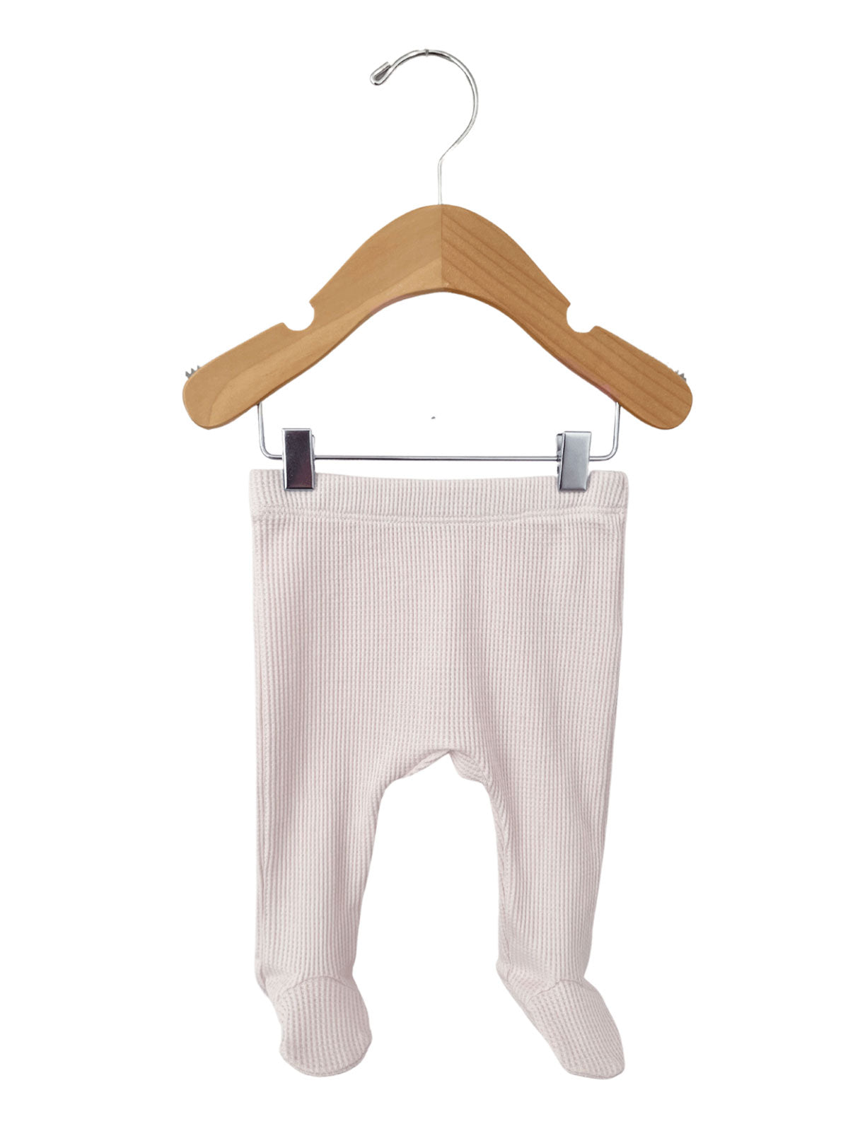 Light pink baby pants hanging on a wooden hanger against a white background.