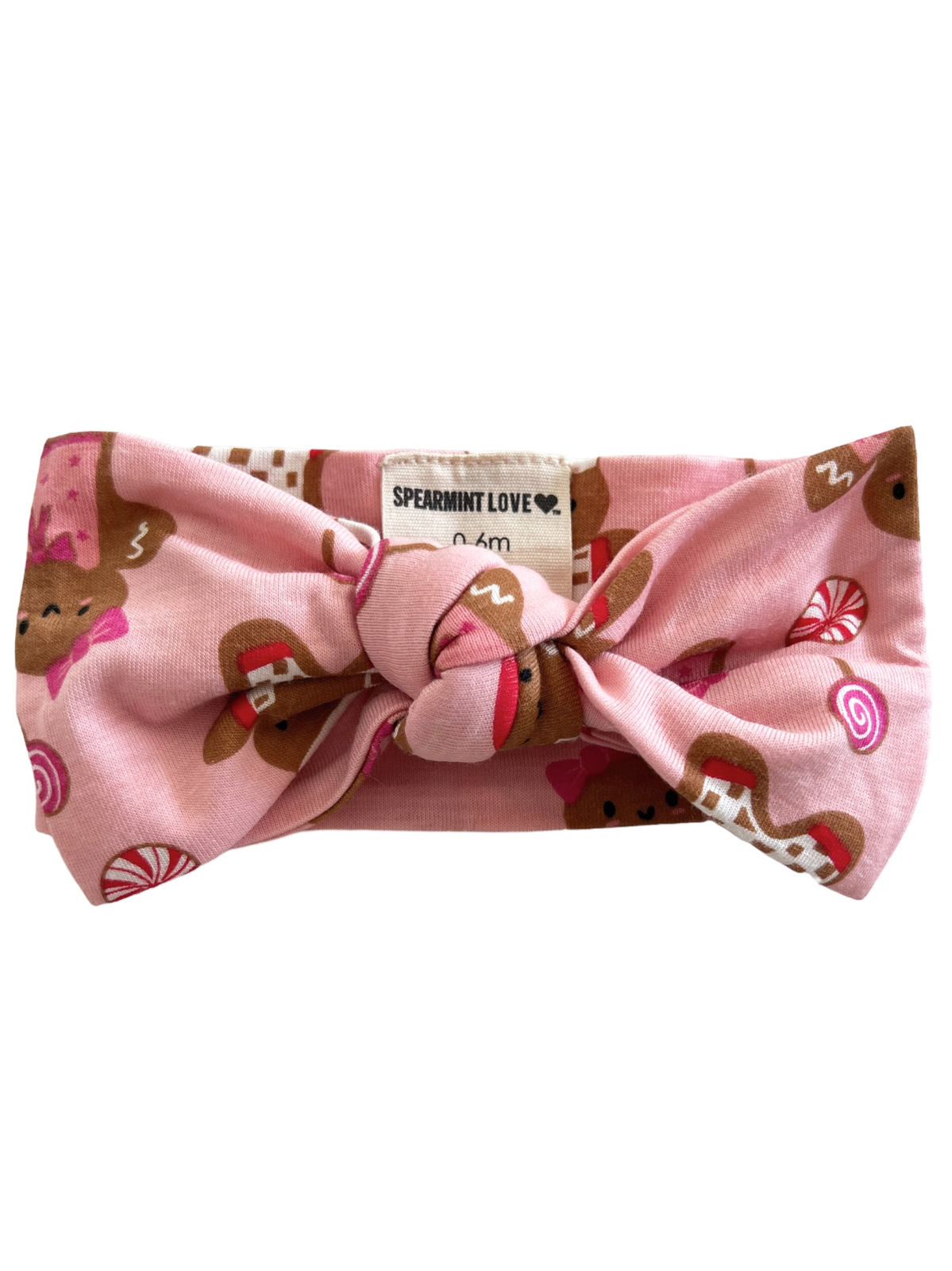 Pink headband with a bow, featuring gingerbread and candy patterns. Label reads "Spearmint Love."