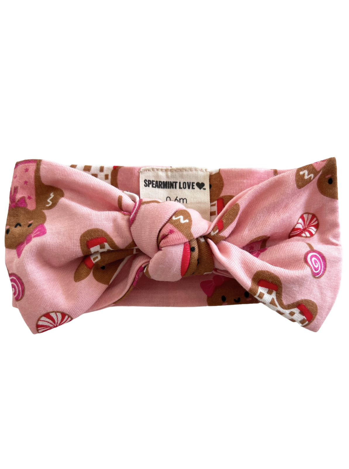 Pink headband with a bow, featuring gingerbread and candy patterns. Label reads "Spearmint Love."