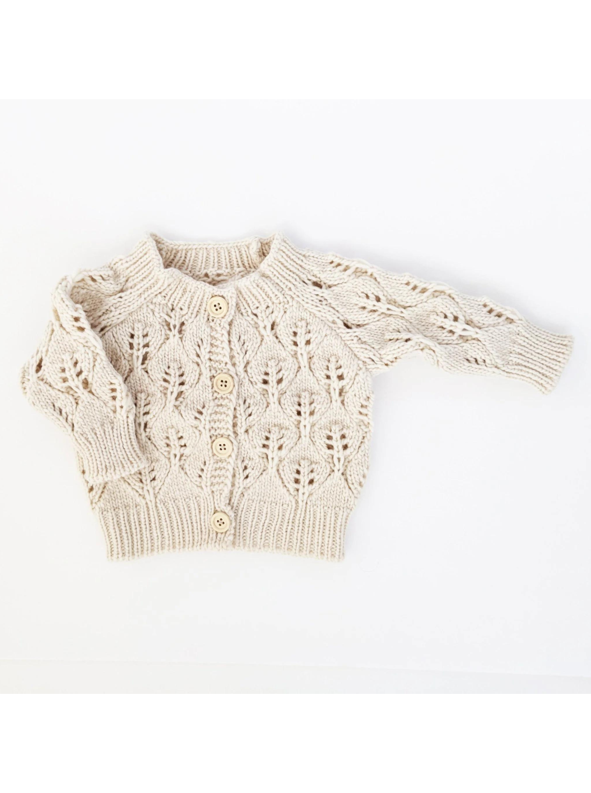 Cream knitted baby cardigan with a textured leaf pattern and wooden buttons.