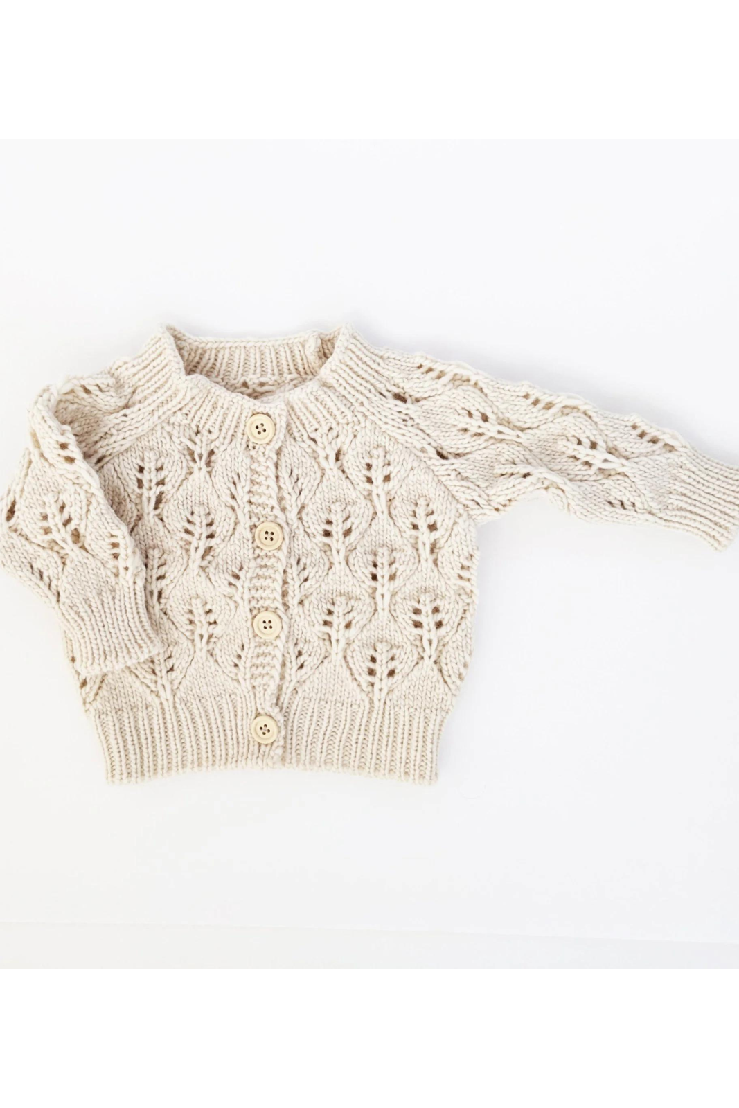Cream knitted baby cardigan with a textured leaf pattern and wooden buttons.