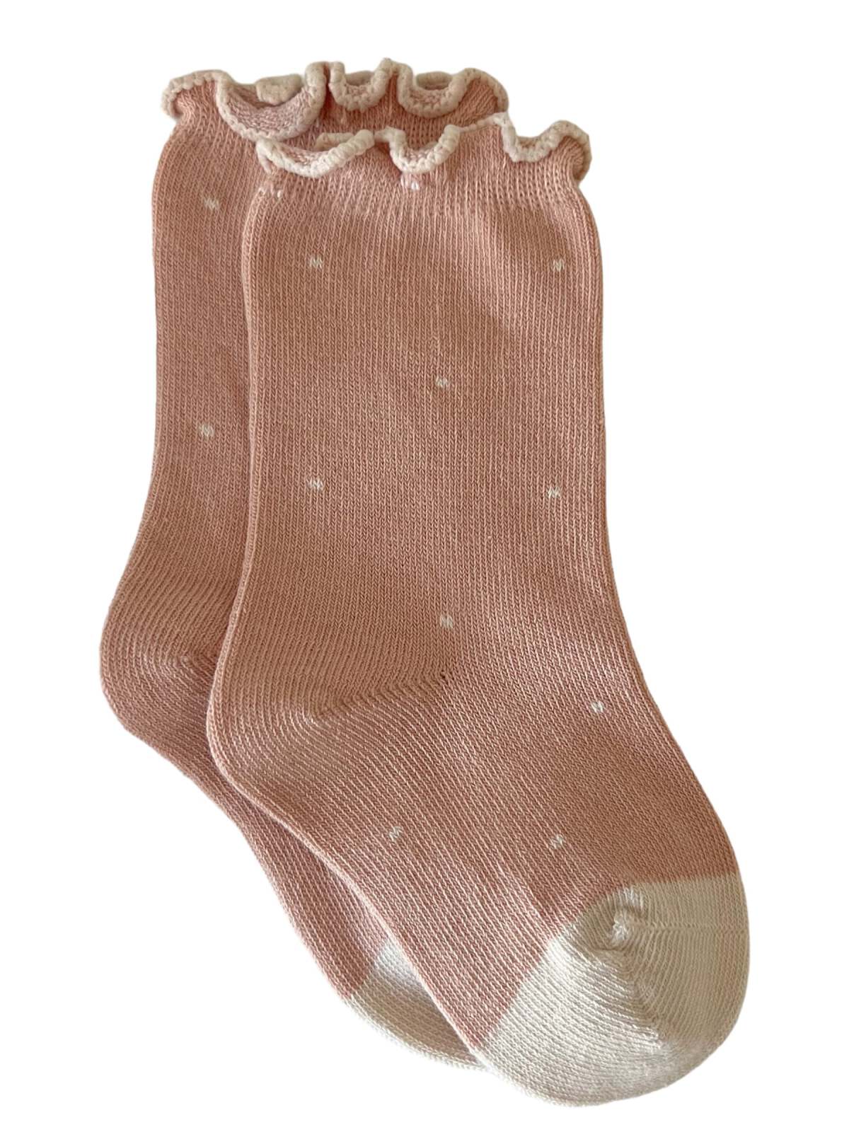 Pink ribbed socks with white polka dots and a ruffled cuff design. Perfect for adding a cute touch to outfits.