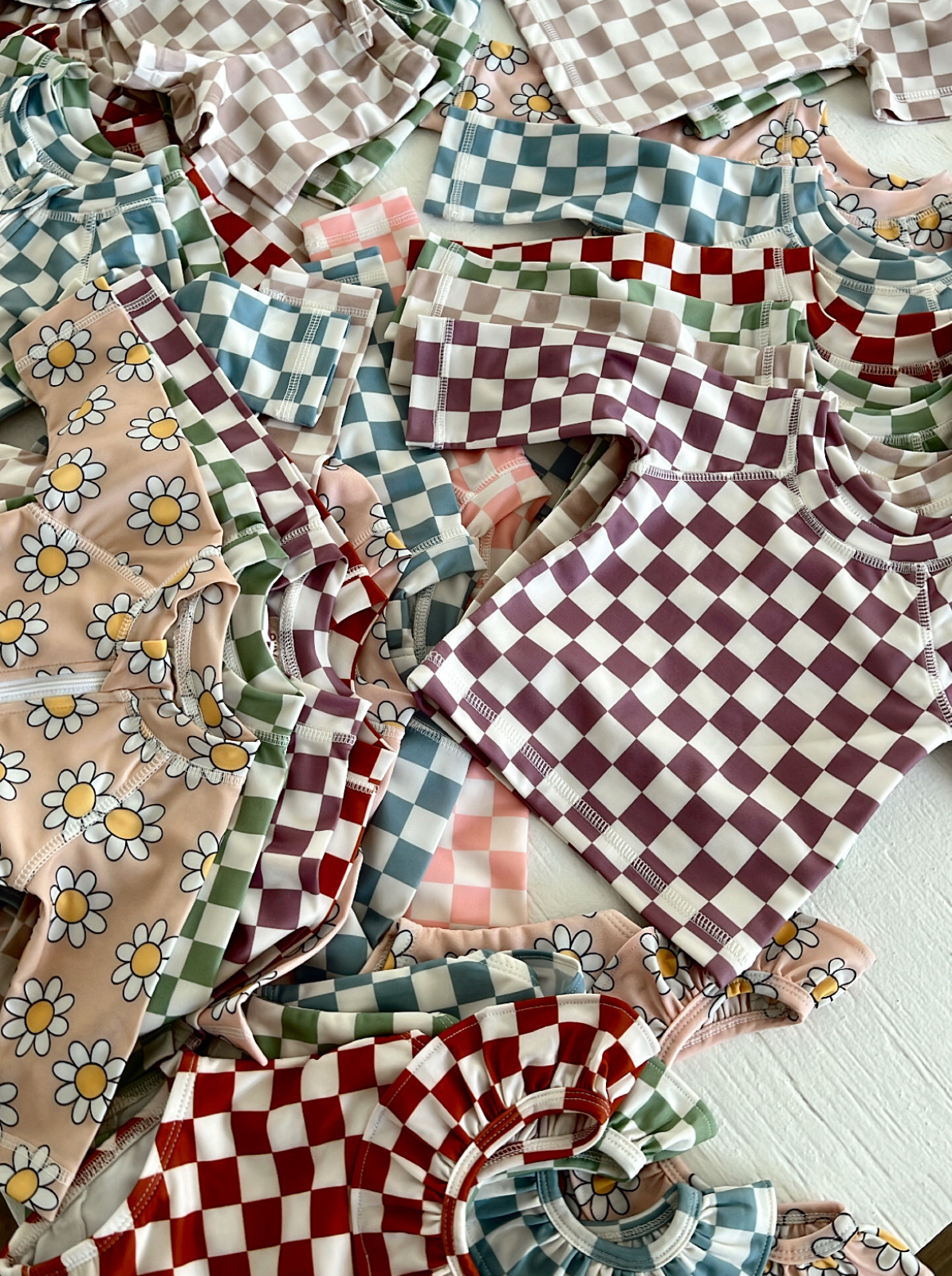 Colorful patterned children's shirts in various designs and colors, including checks and daisies, arranged neatly.