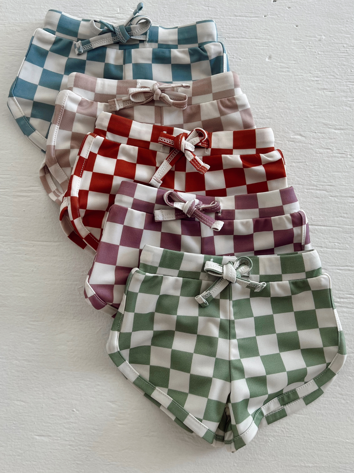 Colorful checkered shorts in various shades stacked on a white surface.
