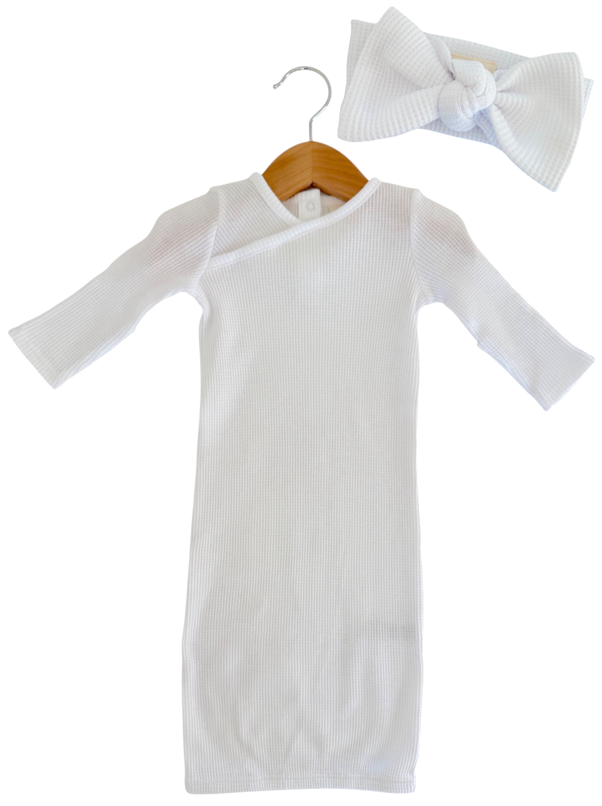 White ribbed dress with long sleeves and a matching bow headband, displayed on a wooden hanger.